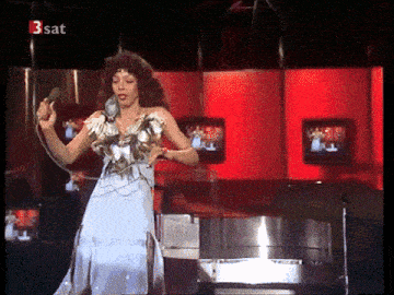 a woman singing into a microphone with the words 3 sat on the bottom right