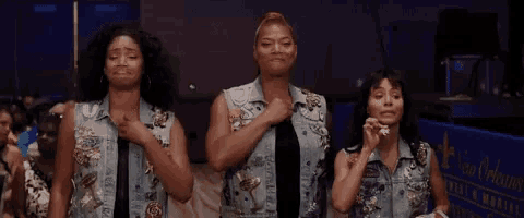 three women wearing denim vests are standing next to each other in a crowd .