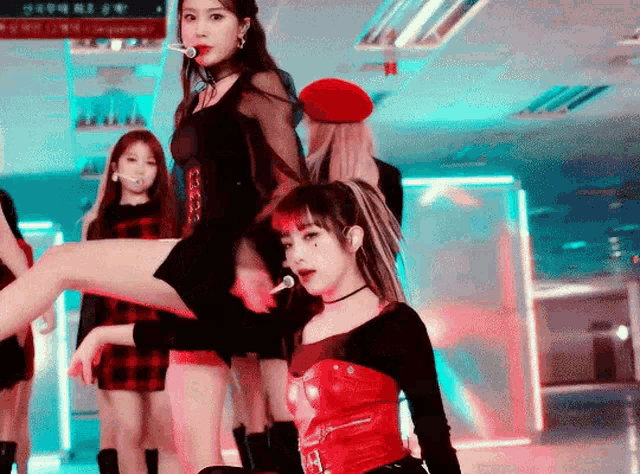 a group of girls are dancing on a stage and one of them is wearing a red corset .
