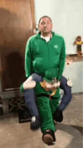 a man in a green jacket is carrying a stuffed animal on his back .
