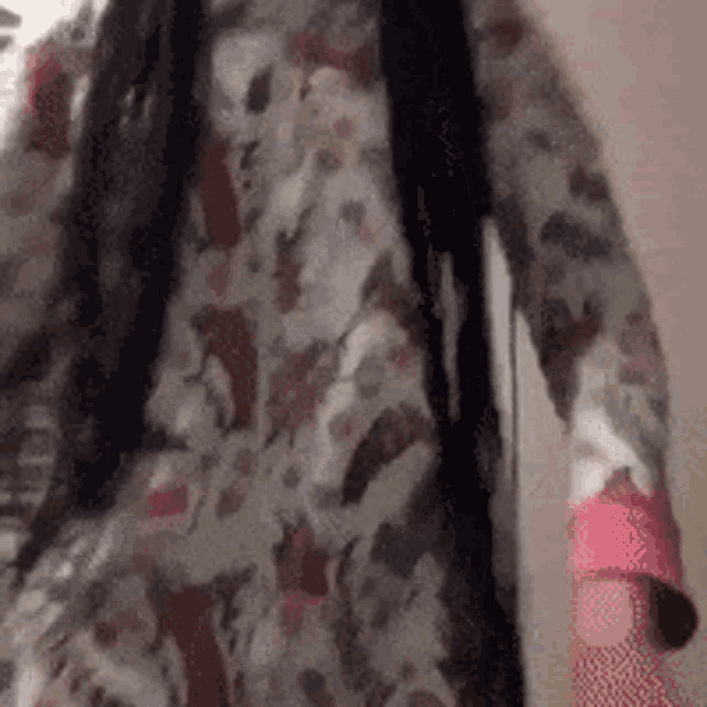 a person wearing a floral shirt and a pink glove is standing in a room .