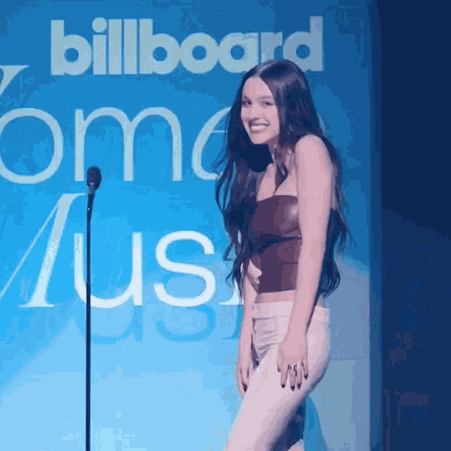a woman stands in front of a sign that says billboard on it