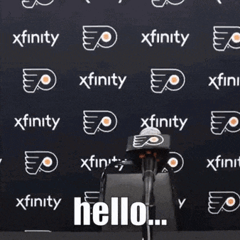 a man in a baseball cap is sitting in front of a microphone and saying hello .
