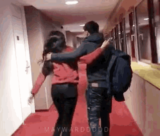 a man and woman are walking down a hallway .