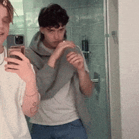 two people are taking a selfie in front of a mirror