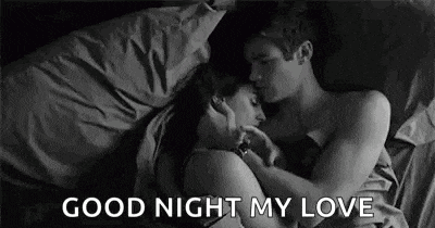 a black and white photo of a man and woman hugging in bed .