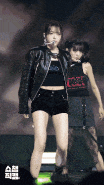 a woman in a leather jacket is standing next to another woman wearing a black tank top that says ' csel ' on it
