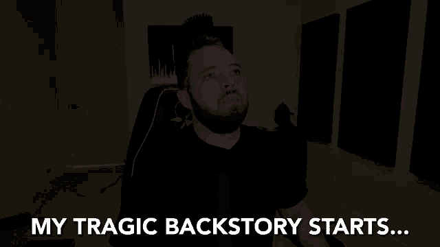 a man with a beard is sitting in a dark room with the words my tragic backstory starts behind him