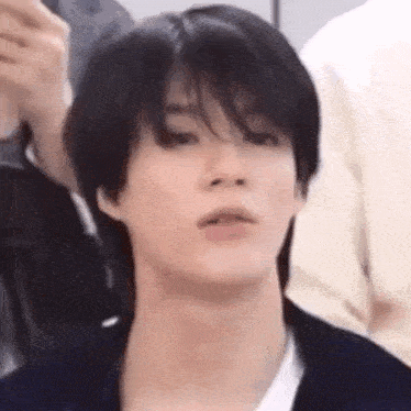 a close up of a person 's face with a black haircut and a white shirt .