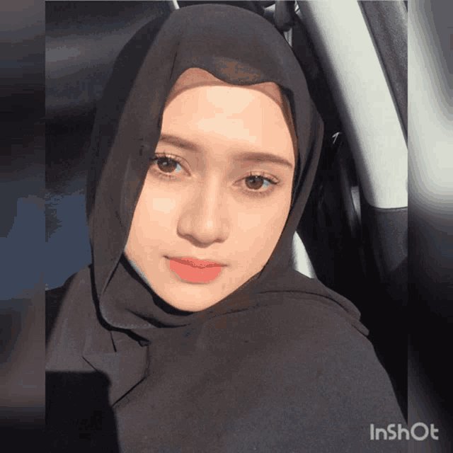 a woman wearing a black hijab is sitting in a car with a watermark that says inshot