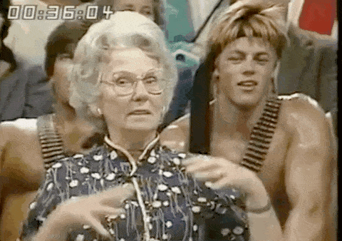 an elderly woman is standing in front of a group of men with guns .