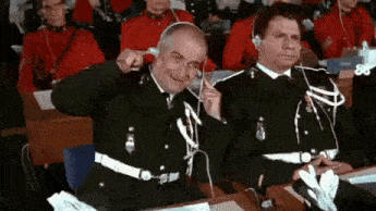 two men in military uniforms are sitting in a classroom with headphones on .