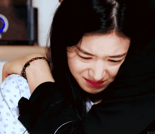a woman in a hospital gown is crying while hugging another woman