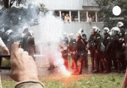 a person is taking a picture of a group of protesters with smoke coming out of them .