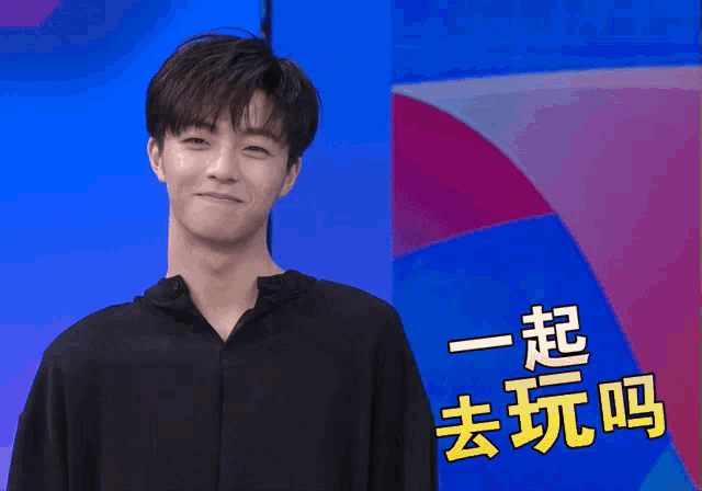 a man in a black shirt stands in front of a blue and pink background