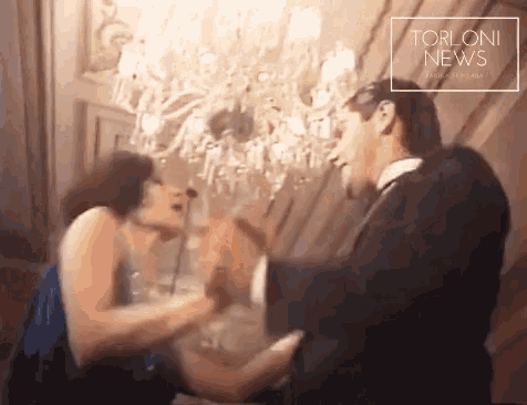 a man and a woman are dancing in front of a chandelier and the words torloni news are on the bottom