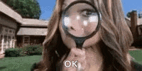 a woman is holding a magnifying glass in front of her face .