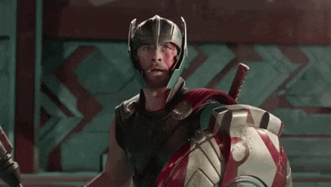 thor is wearing a helmet and holding a sword and shield while screaming .