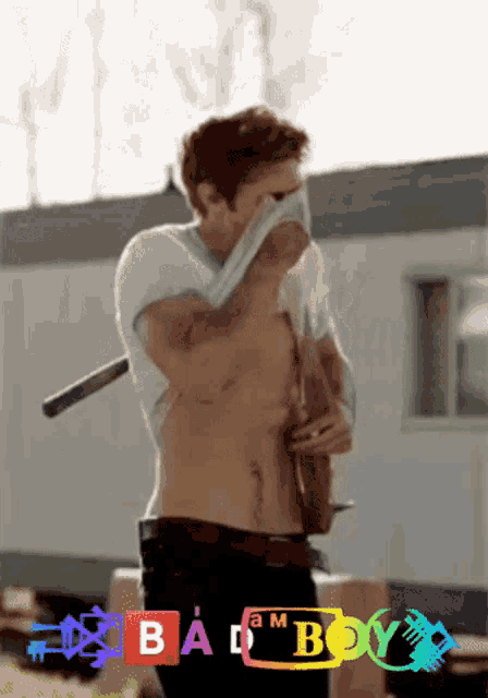 a man without a shirt is holding a guitar in front of a trailer that says bad boy on it