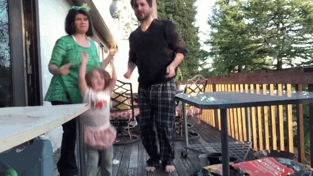 a family dancing on a deck with a table in the background