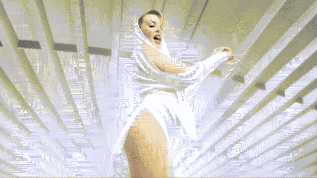 a woman in a white dress is dancing in front of a light beam