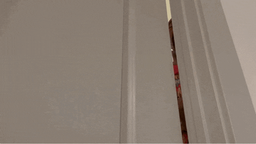 a person in a red shirt is peeking out of a door and giving the middle finger