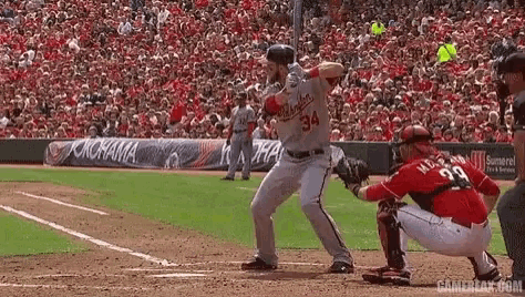 a baseball player is swinging a bat at a pitch while a catcher watches .