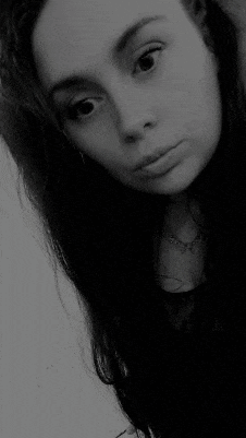 a black and white photo of a young girl with long hair making a funny face .