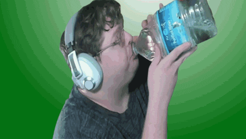 a man wearing headphones drinking from a bottle of water