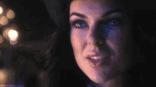 a close up of a woman 's face in a dark room with lights in the background .