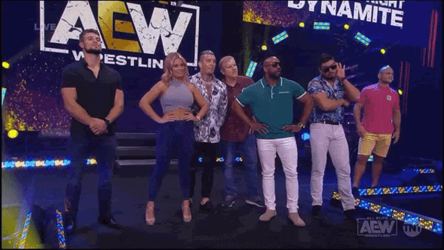 a group of people standing in front of an aew logo