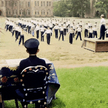 a man in a black hat sits in front of a group of men in white uniforms