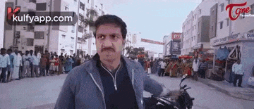 a man is riding a motorcycle down a street in front of a crowd .