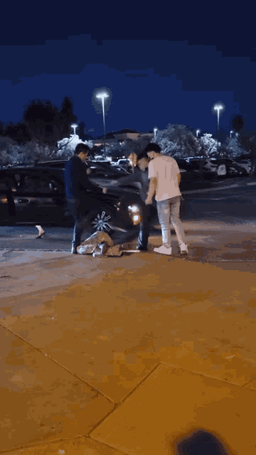 a group of people are standing on a sidewalk at night