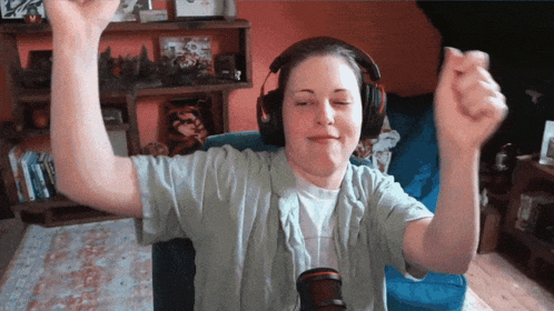 a woman wearing headphones is sitting in a chair with her hands in the air