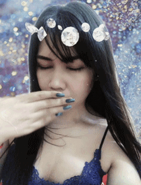 a woman with a crown of diamonds on her head covers her mouth
