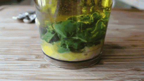 a glass filled with green leaves and yellow liquid
