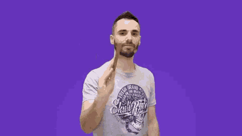 a man wearing a skull ridge t-shirt holds a wooden stick