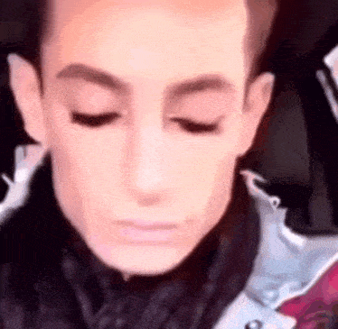 a close up of a person 's face with their eyes closed and a jacket on .