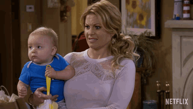 a woman is holding a baby with a netflix logo in the background