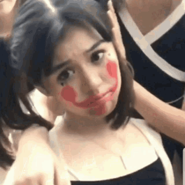a girl with red lipstick on her face is taking a selfie with another girl .