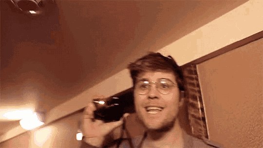 a man wearing glasses is taking a picture of himself with a camera