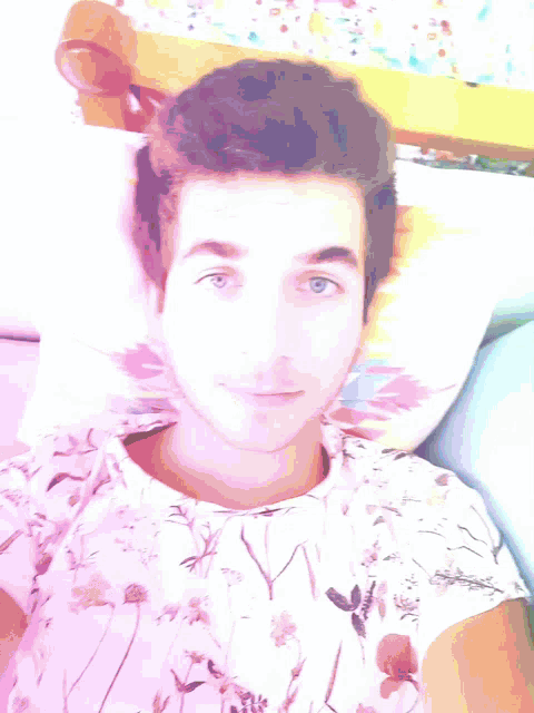 a young man is laying on a bed wearing a floral shirt