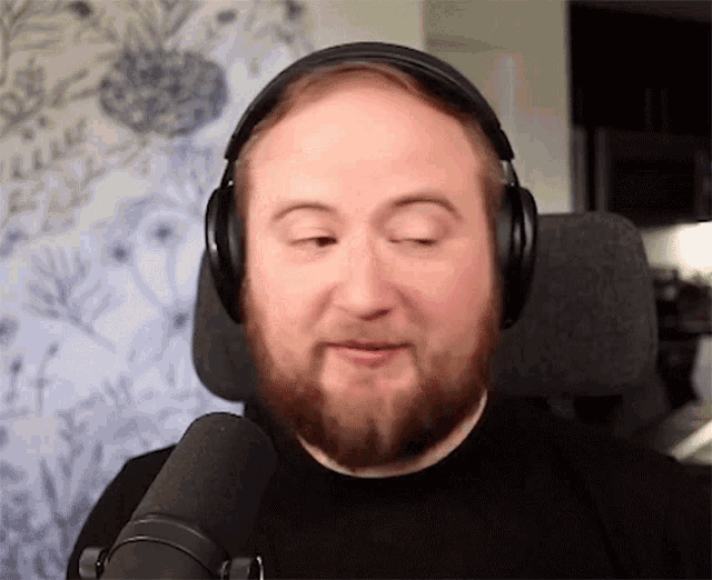 a man with a beard is wearing headphones and making a face