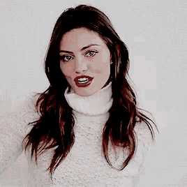 a woman wearing a white turtleneck sweater and red lipstick .