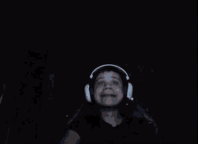a person wearing headphones is making a funny face in a dark room .
