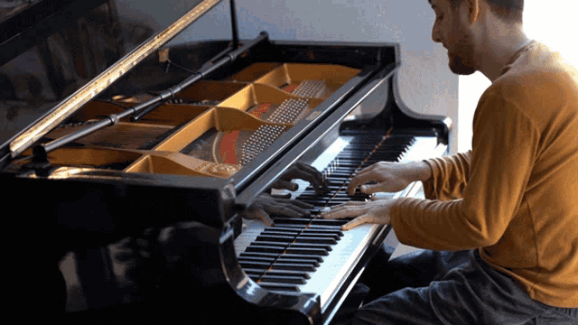 a man in a yellow shirt is playing the piano