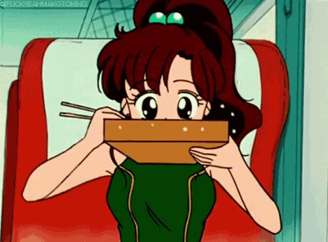 a girl in a green shirt is eating a box of food with chopsticks ..