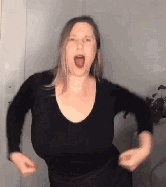 a woman with very large breasts is dancing in a room .