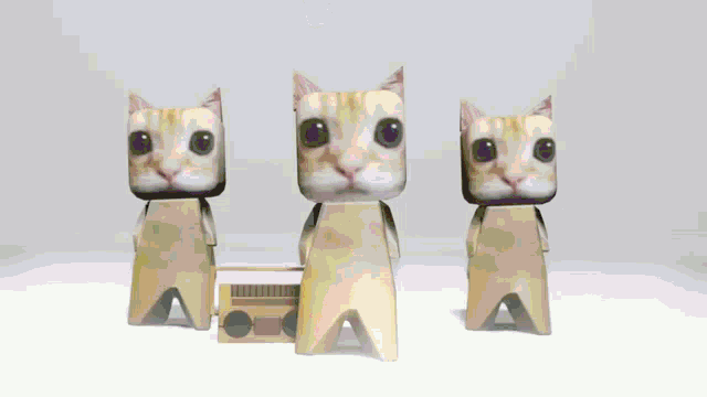 three paper cats are standing next to each other with a radio in their hands